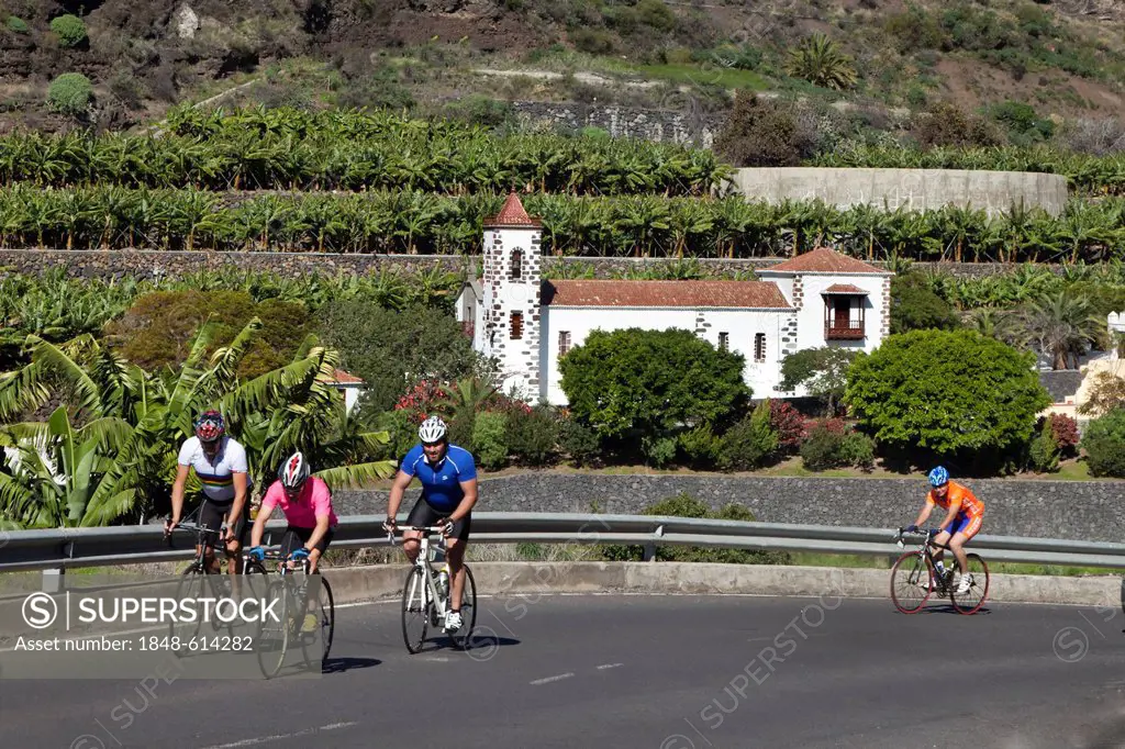Bikers cycling in front of Eremita las Angustias pilgrimage church, La Palma island, Canary Islands, Spain, Europe