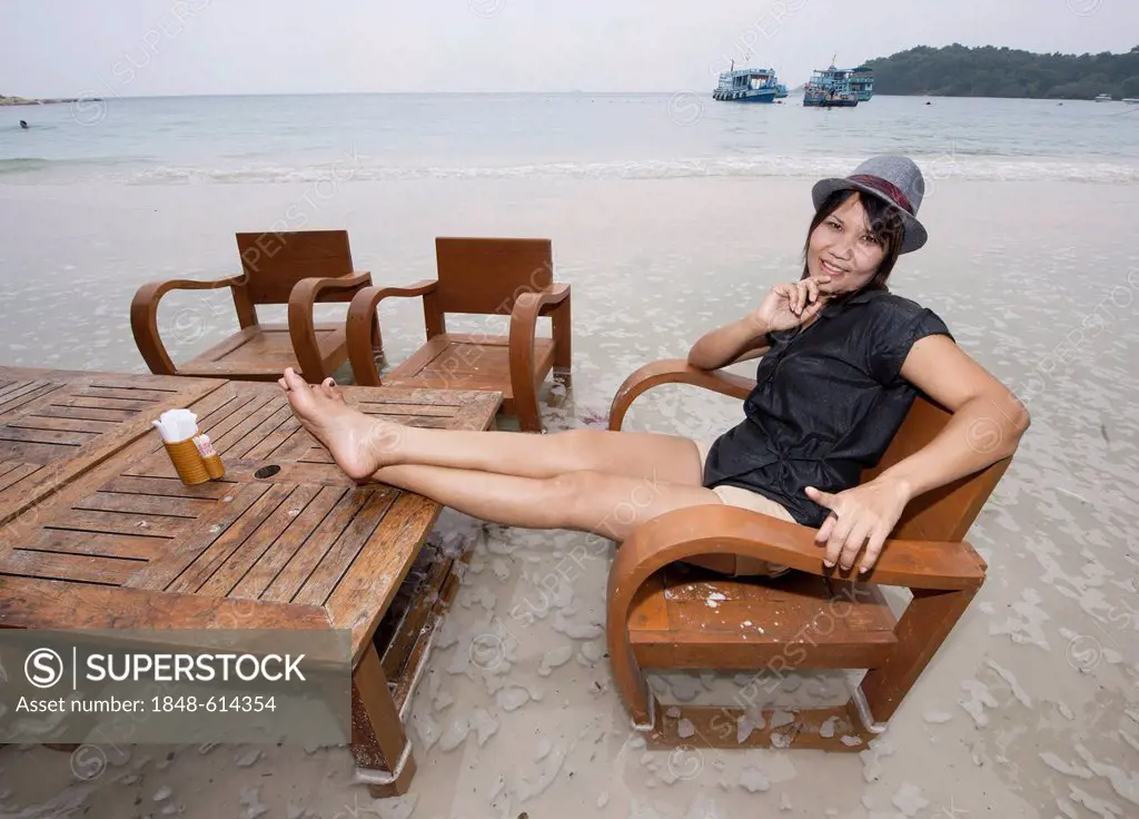 Woman sitting on a flooded beach, Koh Samet, Thailand, Asia