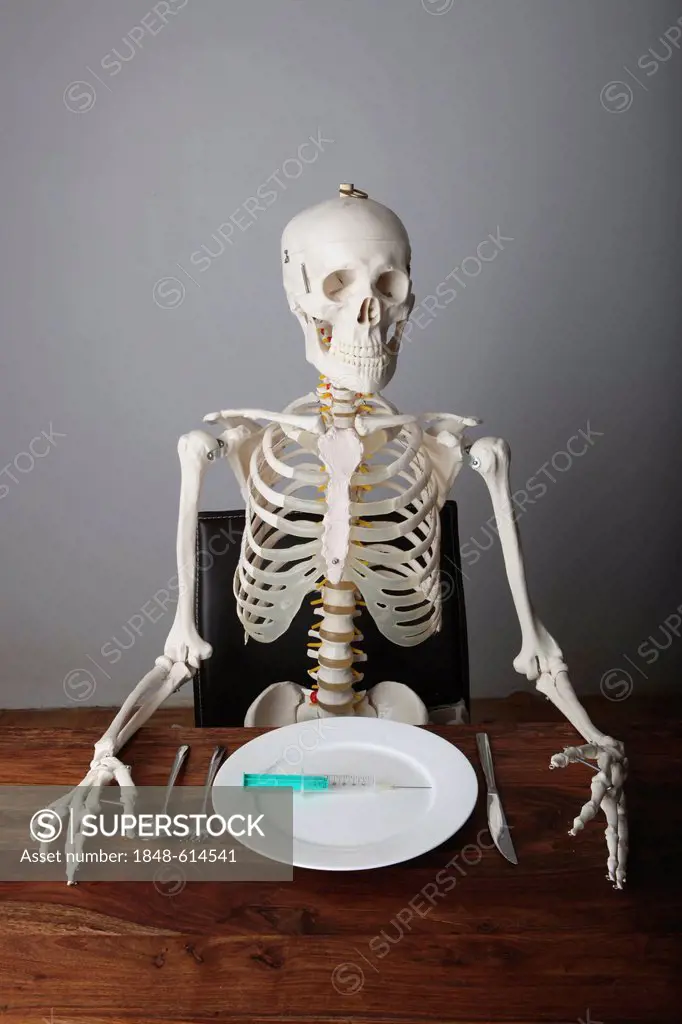 Skeleton sitting at a laid table with a syringe on a plate