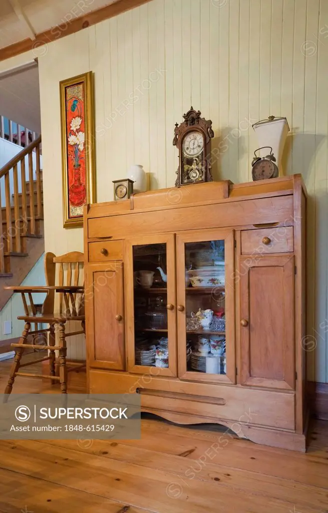 High chair and small dresser in the dining room of an old Canadiana cottage-style residential fieldstone home, circa 1832, Laurentians, Quebec, Canada...
