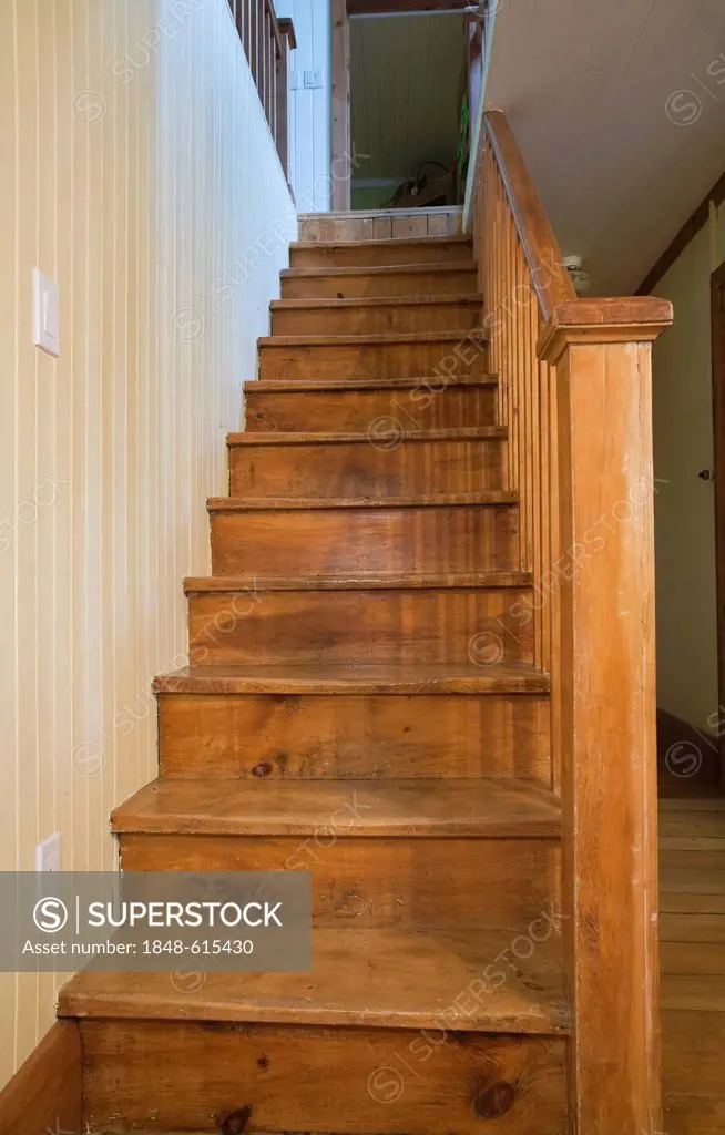 Wooden staircase in the dining room leading to the upstairs floor in an old Canadiana cottage-style residential fieldstone home, circa 1832, Laurentia...