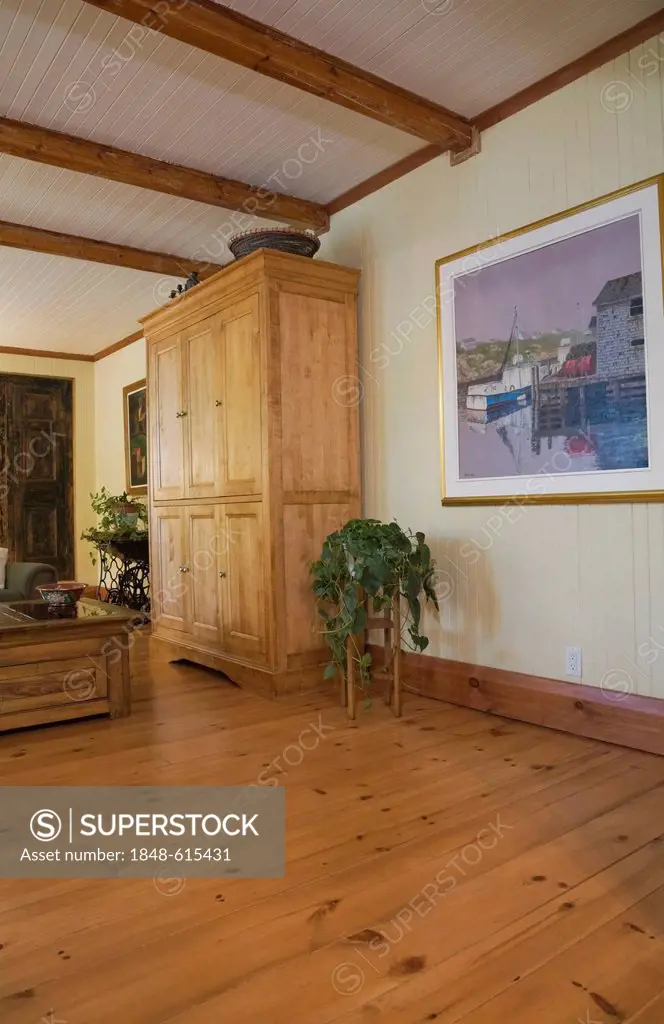 Armoire and furnishings in the living room of an old Canadiana cottage-style residential fieldstone home, circa 1832, Laurentians, Quebec, Canada. Thi...