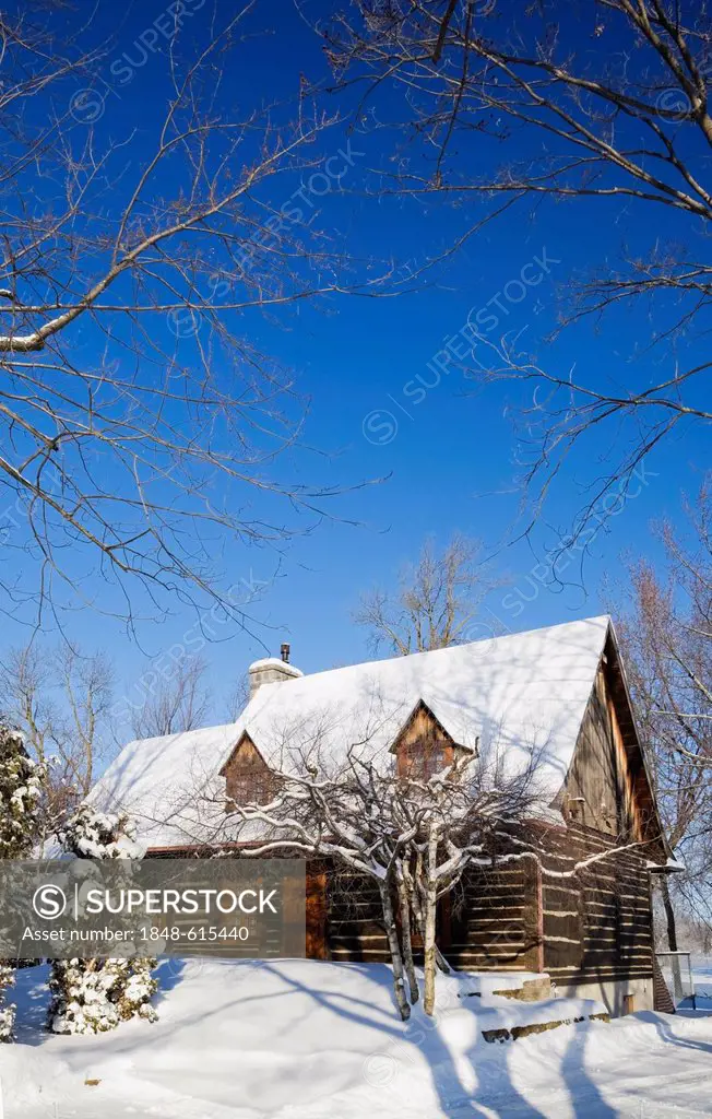 Old reconstructed Canadiana cottage-style residential log home, 1975, in winter, Quebec, Canada. This image is property released for book, calendar, m...