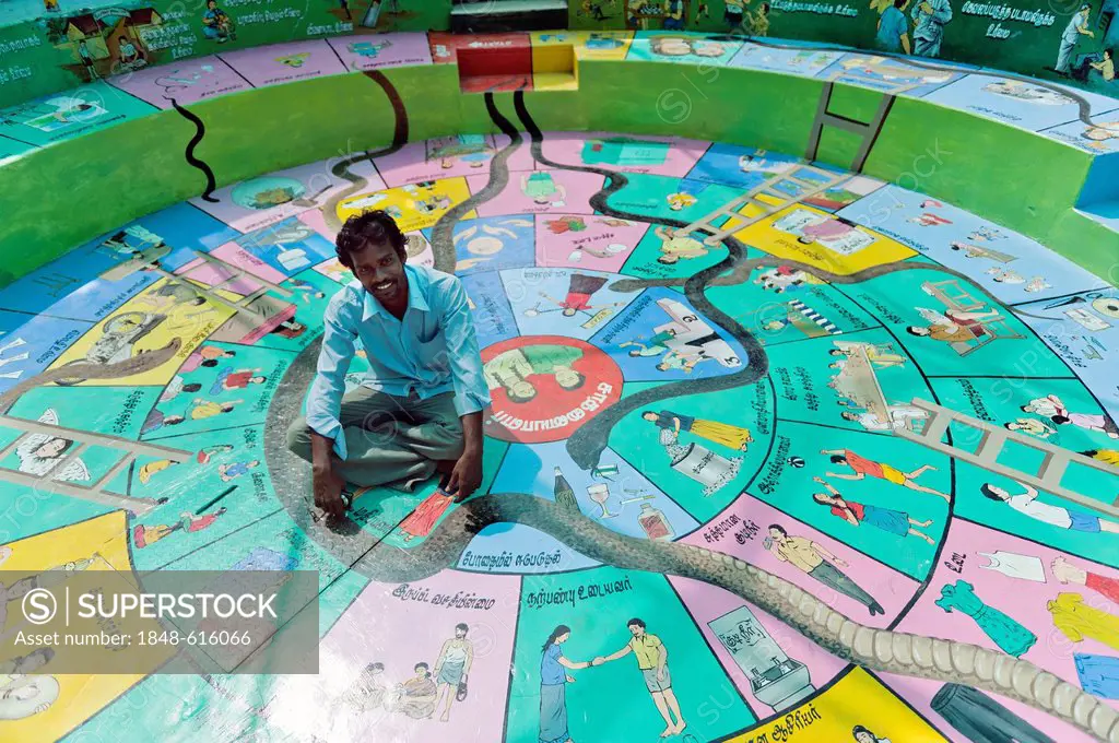 Indian social worker and artist, sitting on huge board game Snakes and Ladders, Indian Moksha Patamu, an education game against child labour, Kutties ...