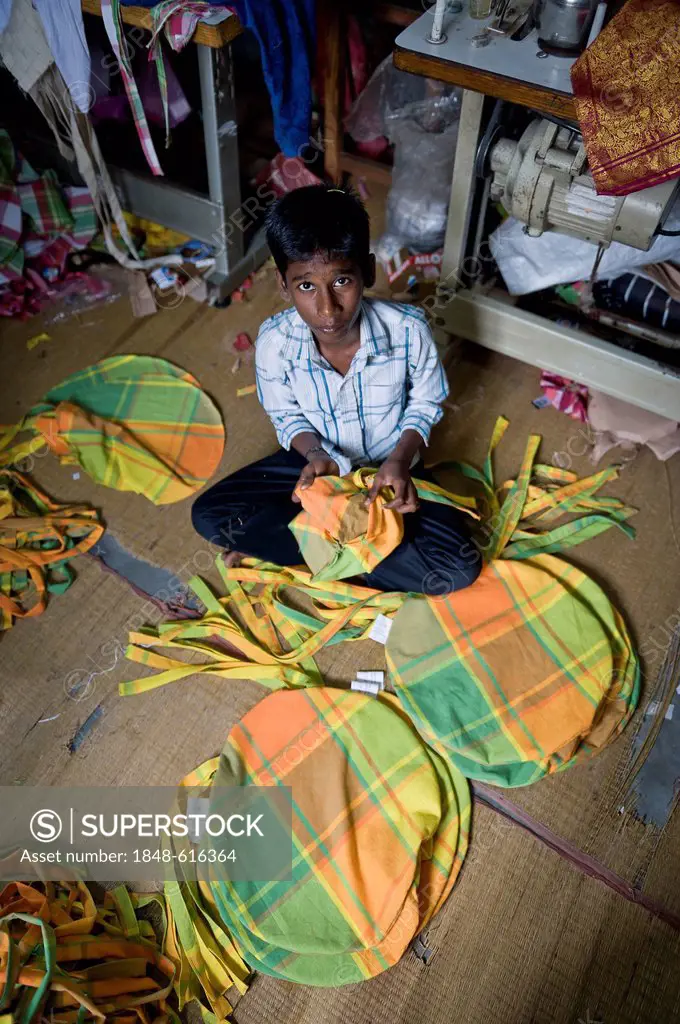 Boy, about 13 years, sewing together colourful cushions in his home, Karur, Tamil Nadu, South India, India, Asia