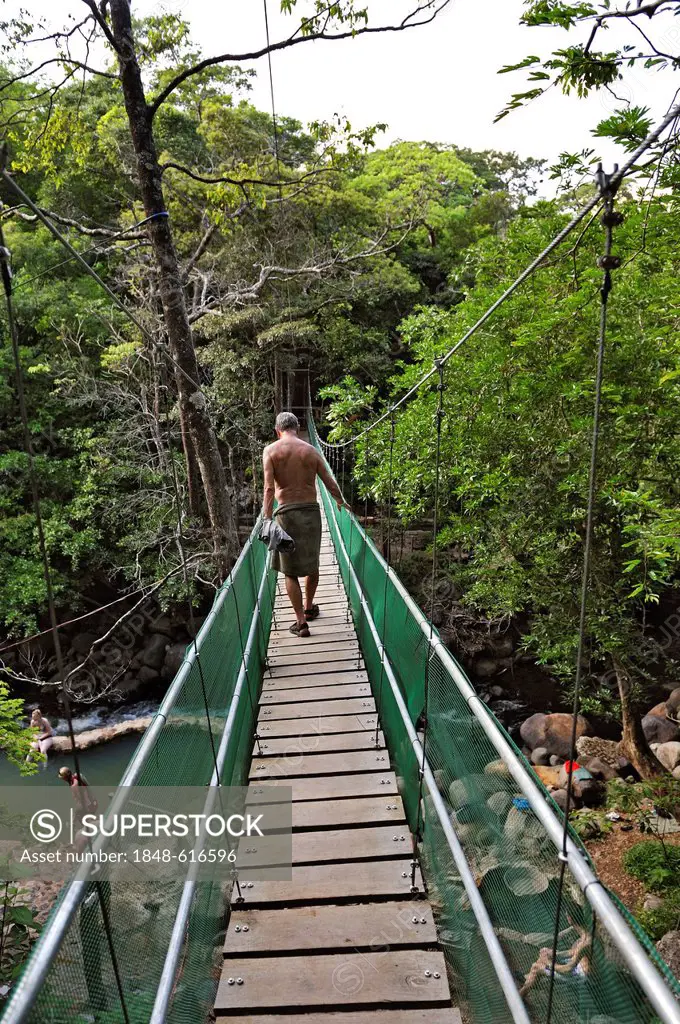 Tourist walking on the suspension bridge leading to the hot springs, near the Hacienda Guachipelin, near Liberia, Guanacaste province, Costa Rica, Cen...
