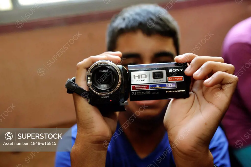 Video course for young people, participant is holding a video camera in his hands for the very first time, organisation El Culebron Timbal, Cuartel V,...