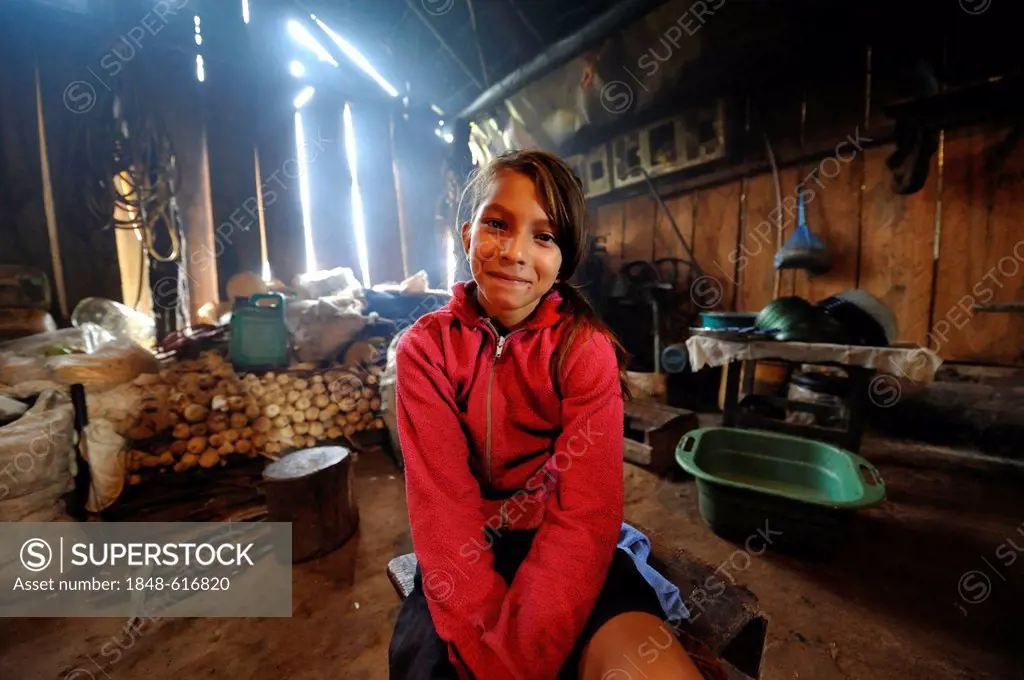 Girl sitting in a simple kitchen of a farmhouse, Comunidad Martillo, Caaguazu, Paraguay, South America