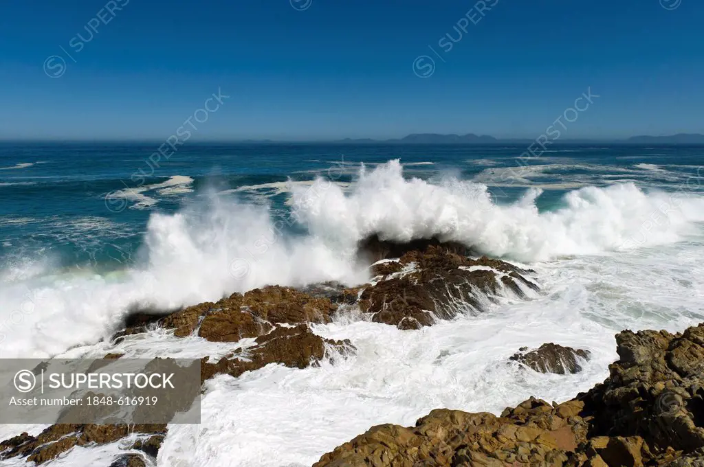 Waves crushing on the bolders along Route 44, Table Mountain at back, Western Cape, South Africa, Africa