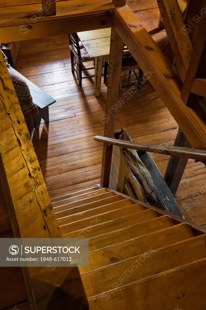 Pinewood stairs leading to the living room on the ground floor of an old Canadiana cottage-style residential log home, circa 1825, Quebec, Canada. Thi...