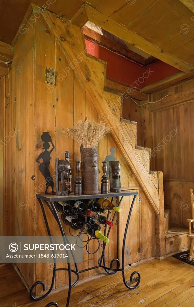 Wine rack in front of an old wooden staircase in an old Canadiana cottage-style residential log home, circa 1840, Quebec, Canada. This image is proper...