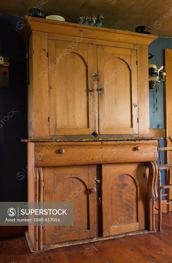 Antique pinewood armoire in the dining room of an old Canadiana cottage-style residential log home, circa 1840, Quebec, Canada. This image is property...