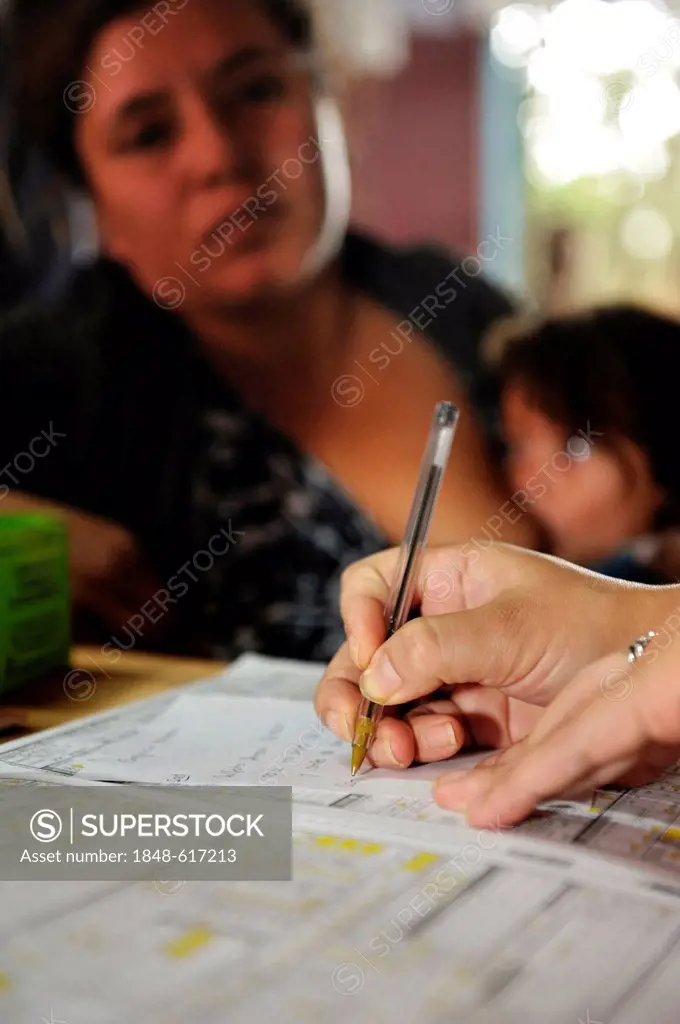 Mother breast-feeding a child, at a medical examination, female doctor completing a form, an aid organisation providing health services and informatio...