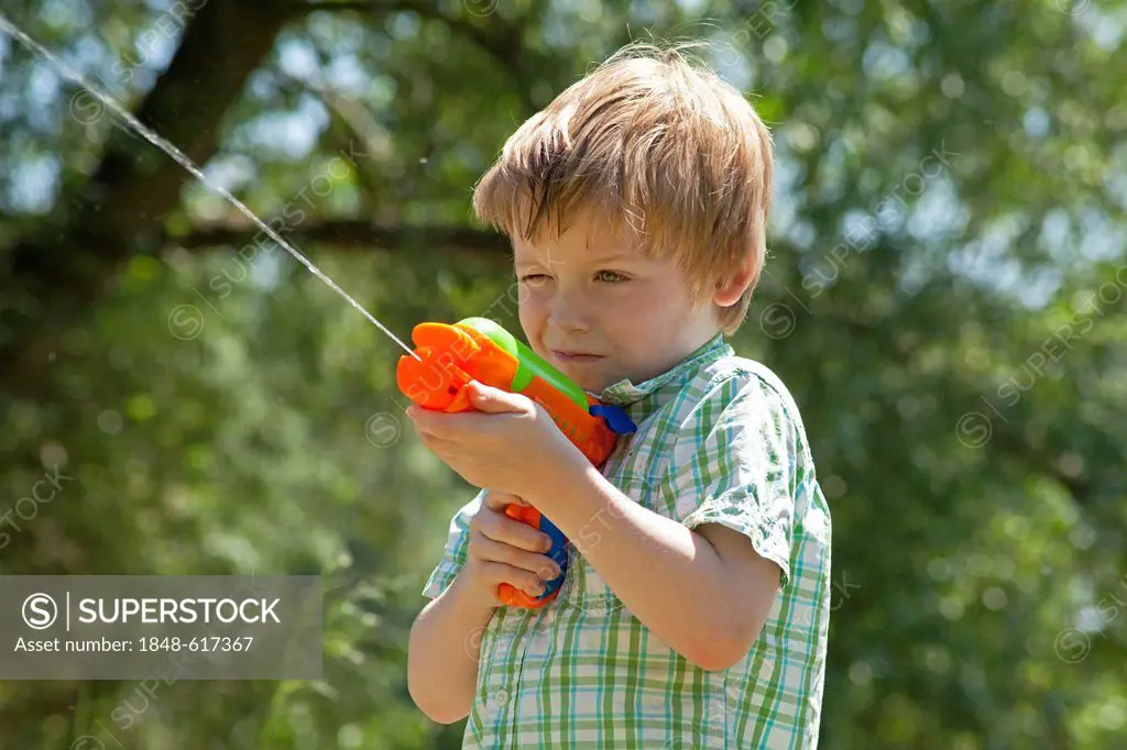 Little boy playing with a water pistol