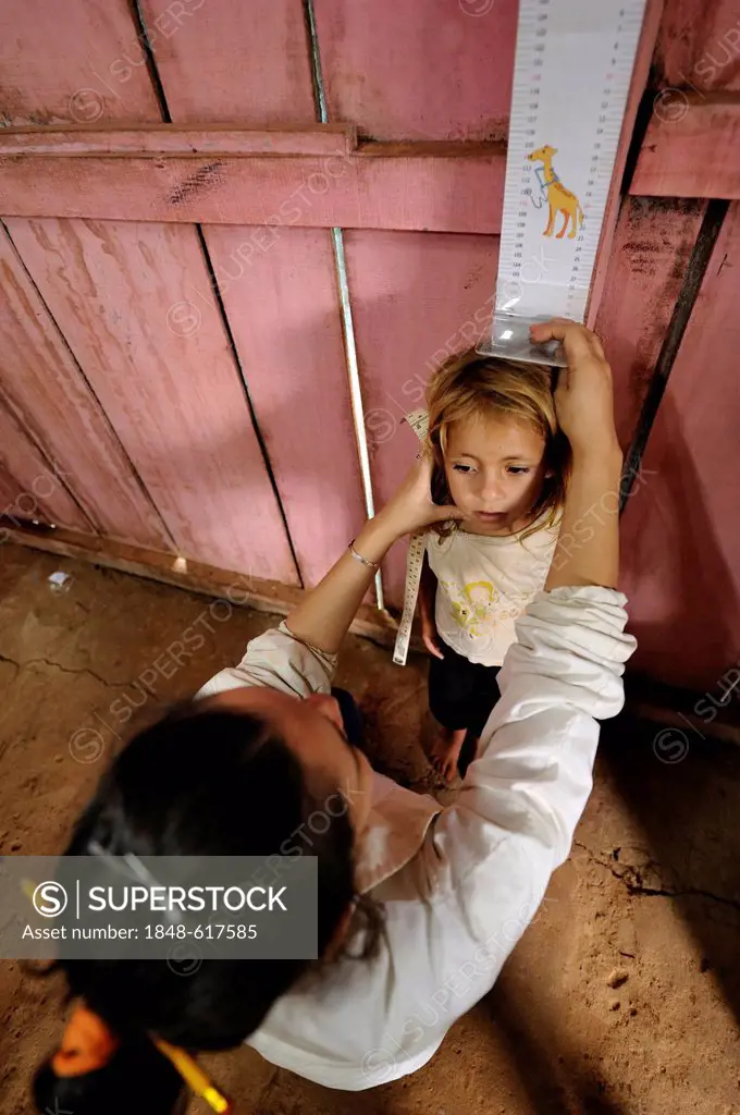 The height of a girl is being measured, an aid organisation examining children in a rural community, Comunidad Martillo, Caaguazú, Paraguay, South Ame...