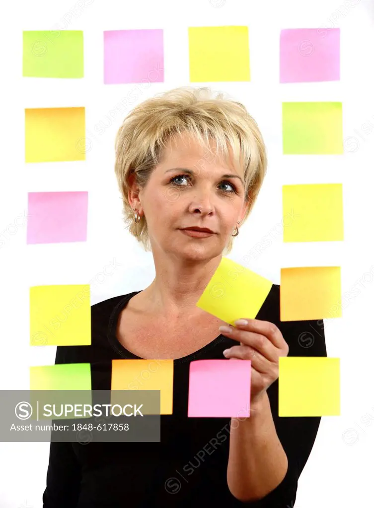 Woman sticking PostIt sticky notes to a sheet of glass