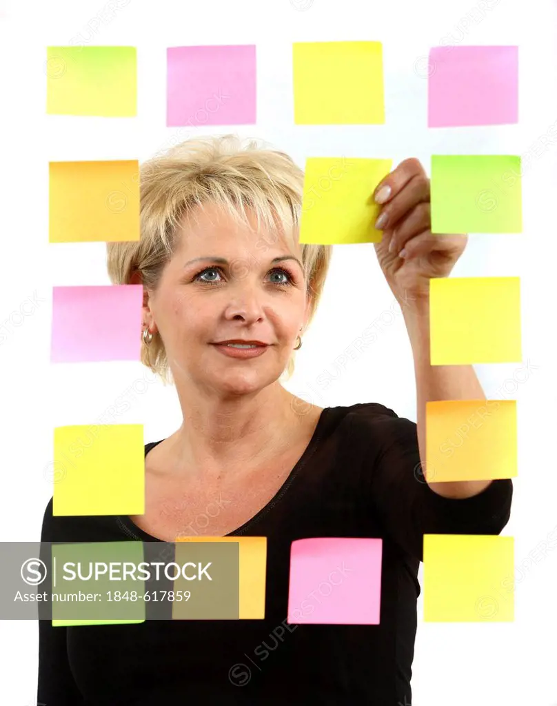 Woman sticking PostIt sticky notes to a sheet of glass