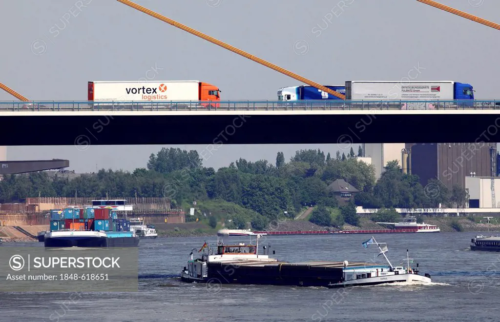 Freight, transport on land an on water, trucks on the A40 motorway, Autobahn, bridge and cargo ships on the Rhine, Duisburg-Rheinhausen, North Rhine-W...