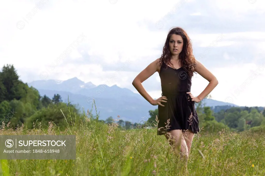 Young woman posing in a short black dress in the long grass