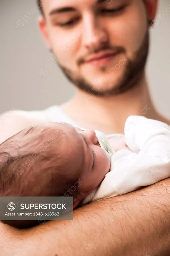 Father lovingly holding his newborn baby in his arms