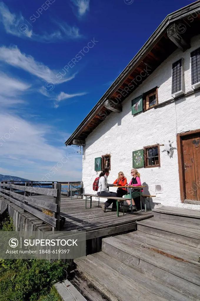 Female hikers taking a break at a private mountain hut on Eggenalm alp, border area between Waidring, Tyrol, Austria, and Reit im Winkl, Chiemgau, Bav...