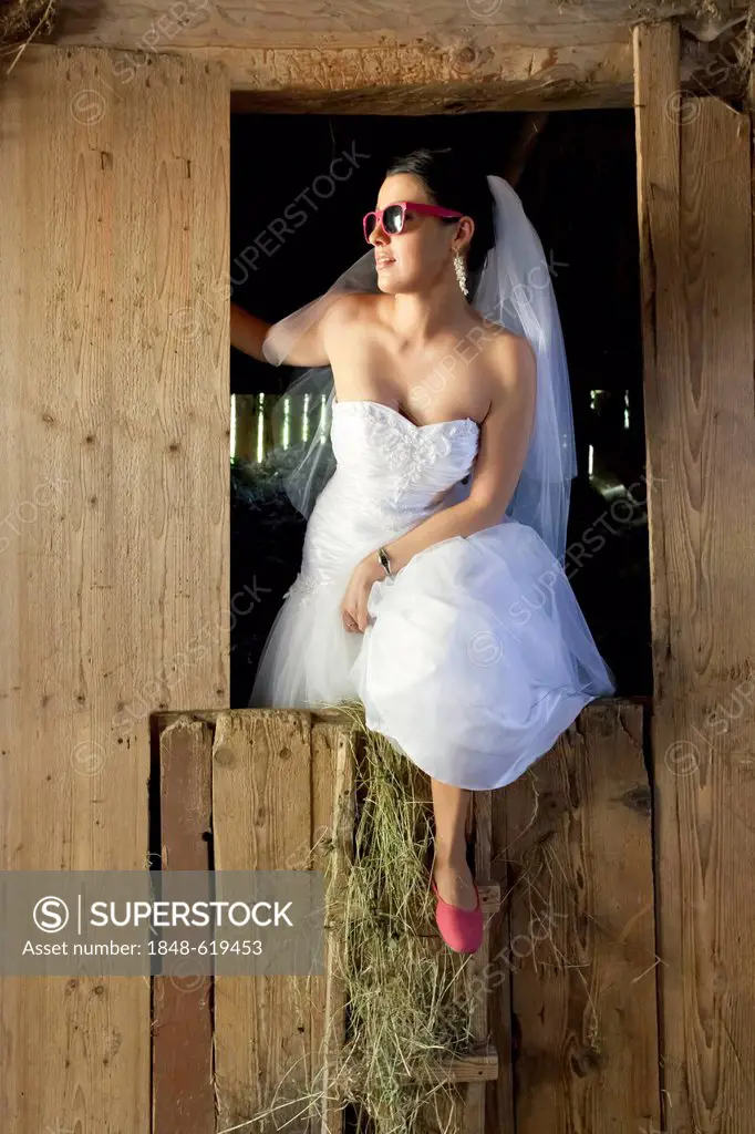 Bride looking out of a barn, hay shed