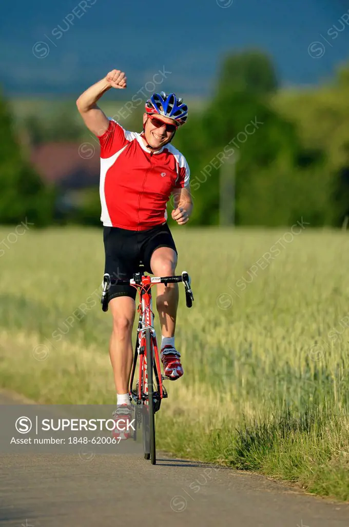 Racing cyclist riding a bicycle, arm raised in a victory pose, jubilation, Waiblingen, Baden-Wuerttemberg, Germany, Europe, PublicGround
