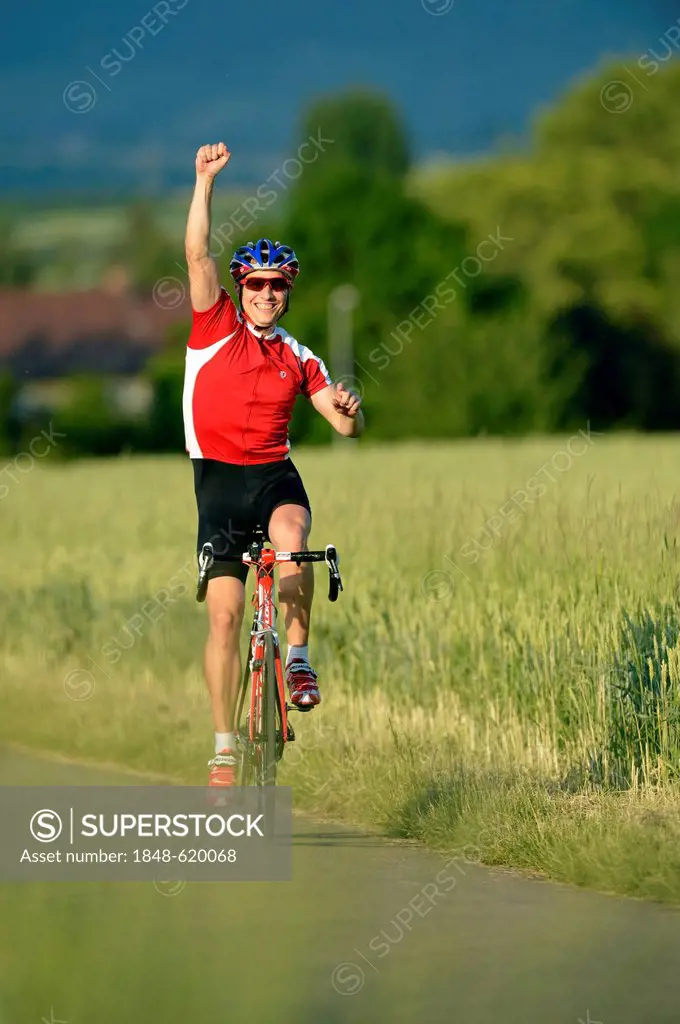 Racing cyclist riding a bicycle, arm raised in a victory pose, jubilation, Waiblingen, Baden-Wuerttemberg, Germany, Europe, PublicGround