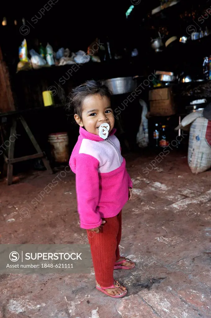Little girl with a pacifier, smiling, standing in the simple kitch of farm workers, Comunidad Arroyito, Departamento Concepcion, Paraguay, South Ameri...