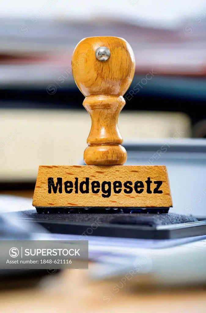 Rubber stamp with the wording Meldegesetz, German for registration law, on a desk