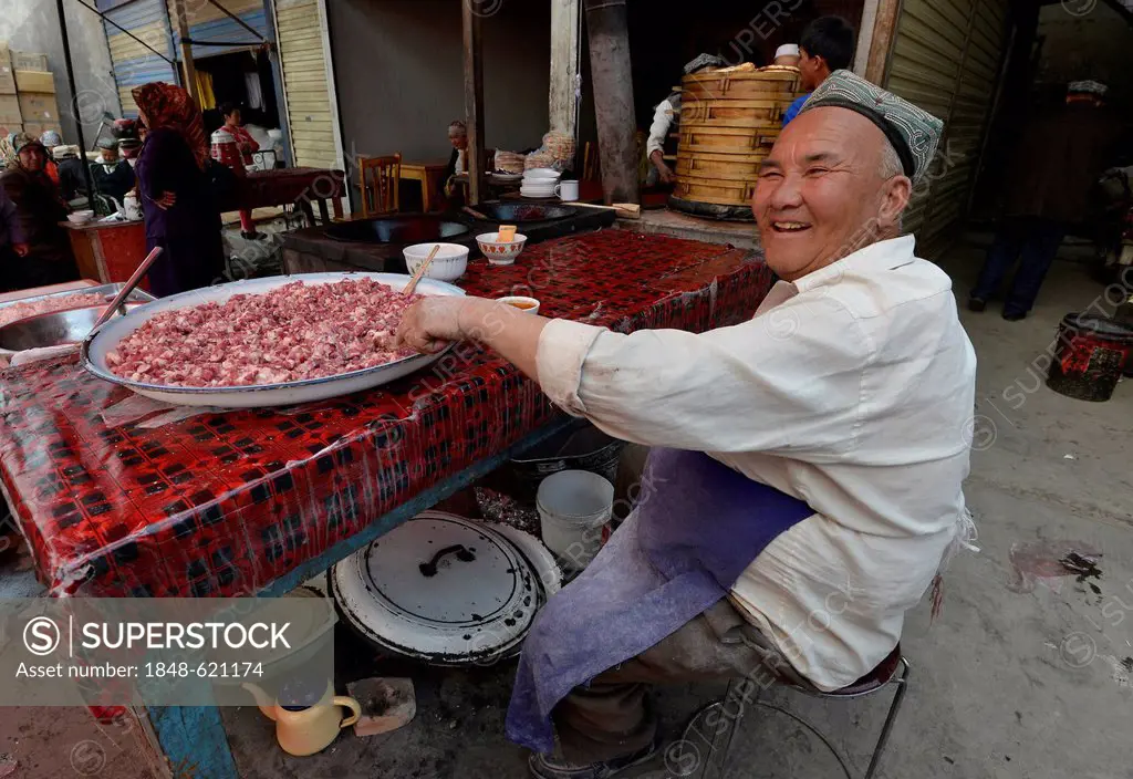 Sunday market, elderly Uyghur man with a traditional hat selling minced mutton, Muslim bazaar, Uighur, Kashgar, Xinjiang, China, Asia