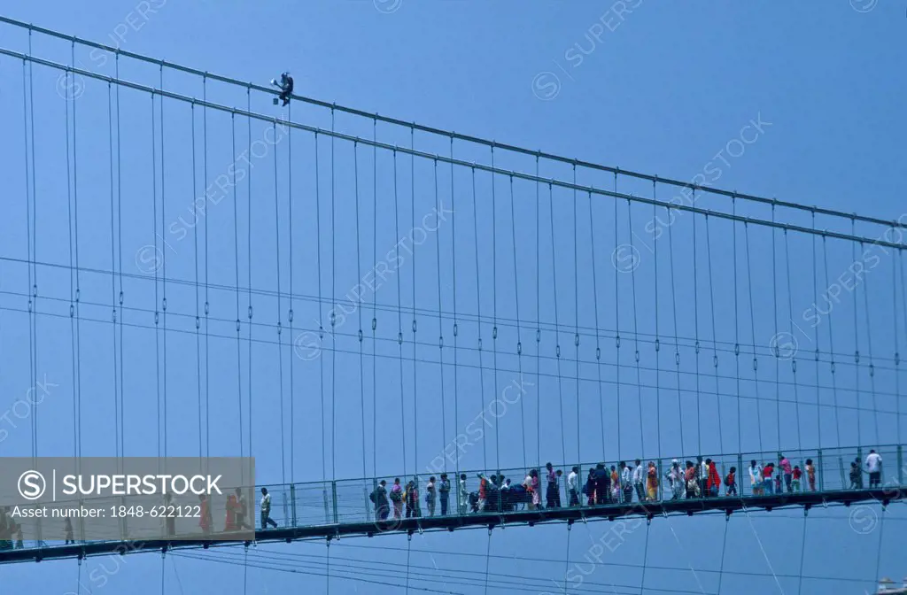 Ram Jhula bridge across the River Ganges with many pilgrims and a painter at the top, Rishikesh, Uttaranchal, India, Asia