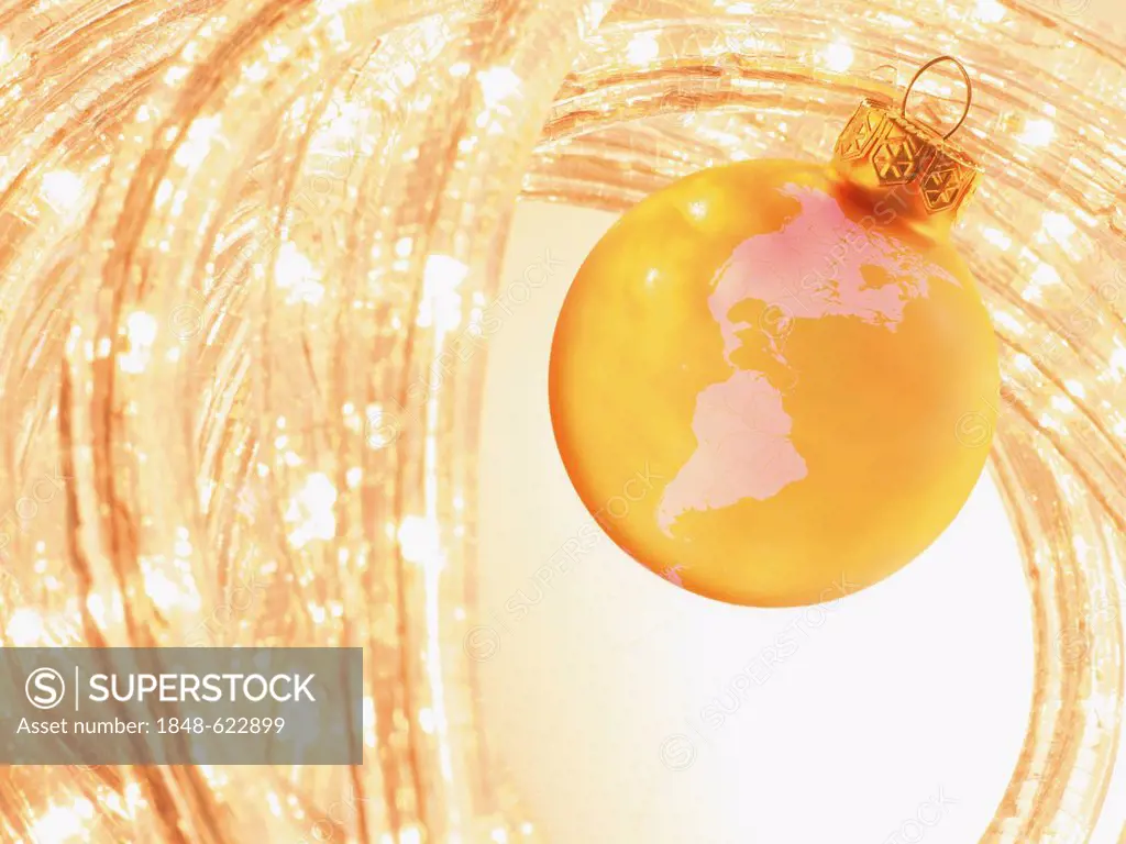 Golden Christmas bauble with a map of North America and South America, and fairy lights