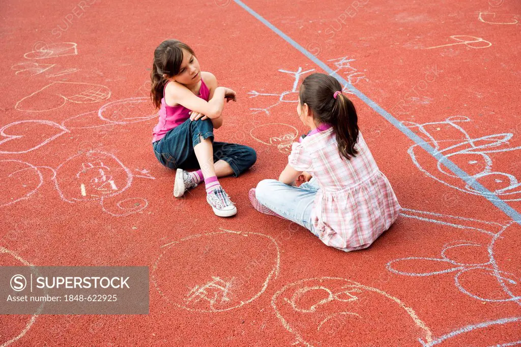 Two girls sitting around bored on the school playground