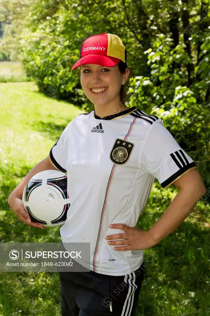 Young woman wearing a Germany cap and jersey, holding a football