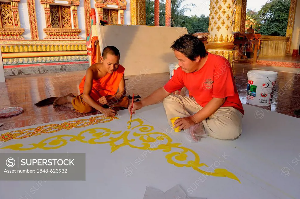 A monk and a craftsman painting ceiling panels on the floor of a Buddhist temple, Vang Vieng, Laos, Southeast Asia
