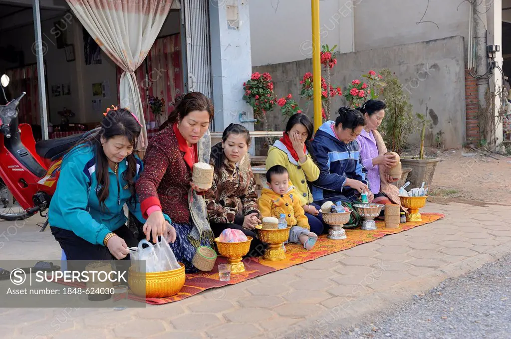Early in the morning, a Buddhist family is waiting with offering for the Buddhist mendicants in the town of Phansavan, Laos, Southeast Asia, Asia