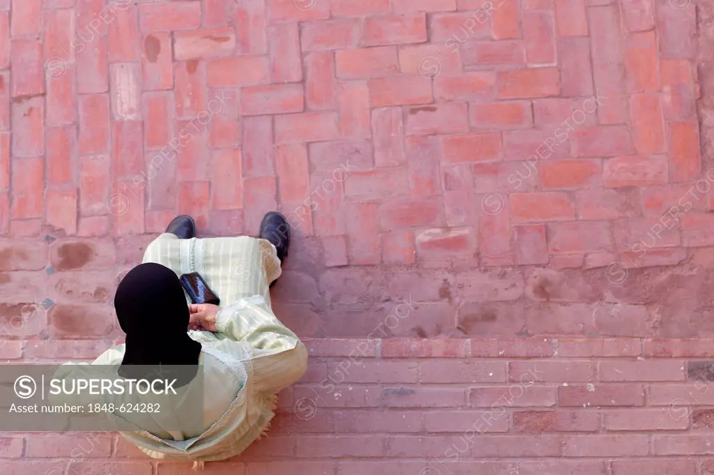 Local woman sitting on a bench made of bricks, Ouarzazate, Souss-Massa-Dra, Morocco, Maghreb, North Africa, Africa