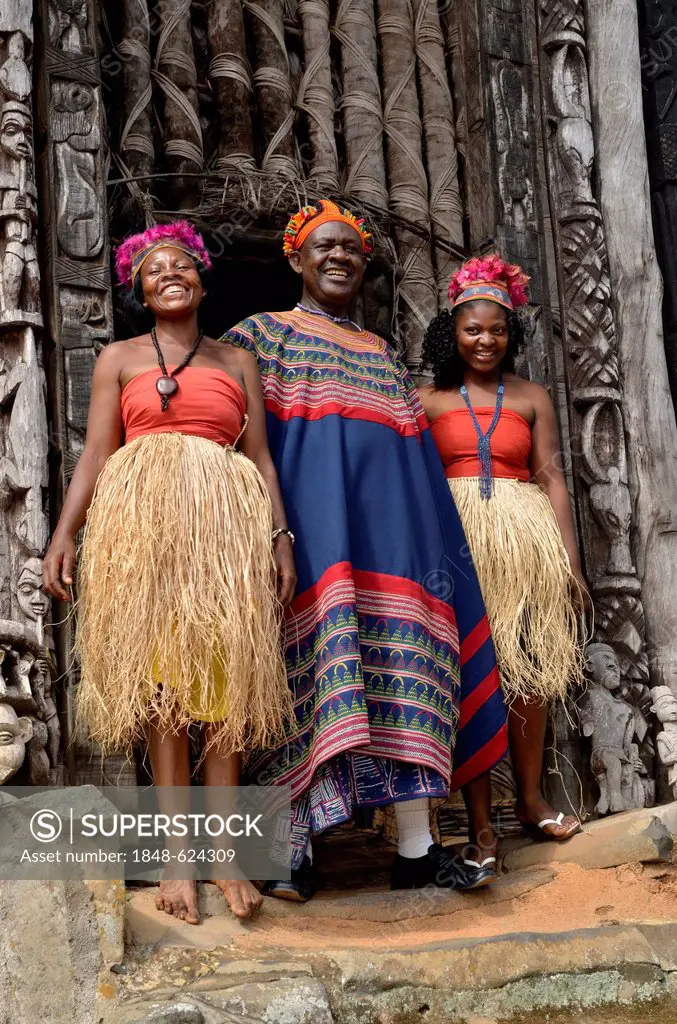 King Fon Abumbi II, head of one of the traditional kingdoms in north west Cameroon, in front of the Achum sanctuary at his seat of power with two of h...