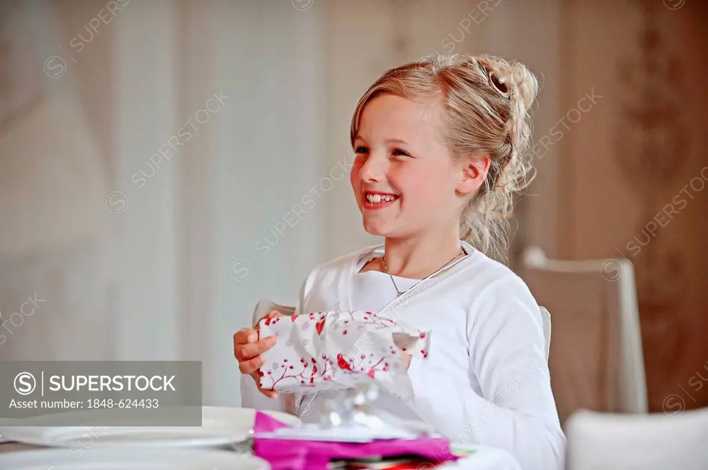 Girl, 9 years, unwrapping gift on her First Communion day, Muensterland region, North Rhine-Westphalia, Germany, Europe