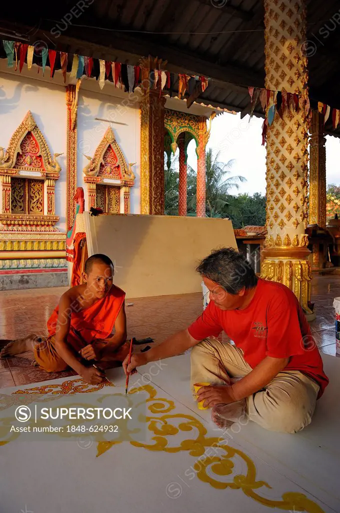 A monk and a craftsman painting ceiling panels on the floor of a Buddhist temple, Vang Vieng, Laos, Southeast Asia