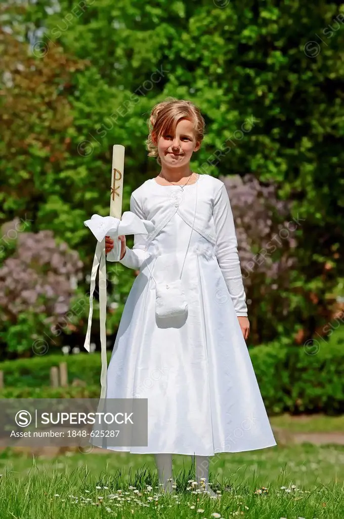 Girl, 9 years, in a white First Communion dress holding a communion candle, First Communion, Muensterland region, North Rhine-Westphalia, Germany, Eur...