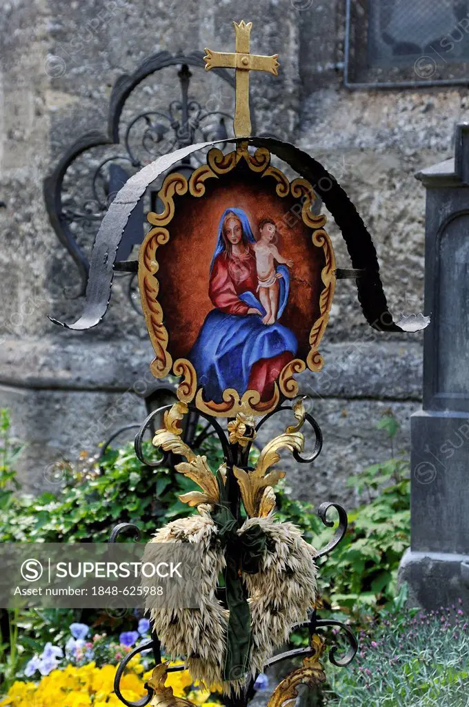 Old colourful wrought-iron cross on a grave with a religious motif, St. Peter's Cemetery, oldest Christian burial site of Salzburg, Sankt Peter distri...