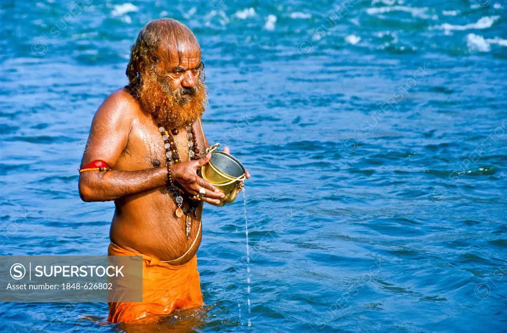 Sadhu, holy man, doing his washing and praying ceremony in the morning at the holy Narmada river, Omkareshwar, India, Asia