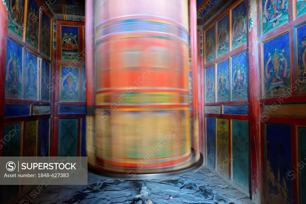 Tibetan Buddhism, wooden painted prayerwheel covered in Buddhist symbols, in motion, kora at the Labrang Monastery, Xiahe, Gansu, formerly Amdo, Tibet...