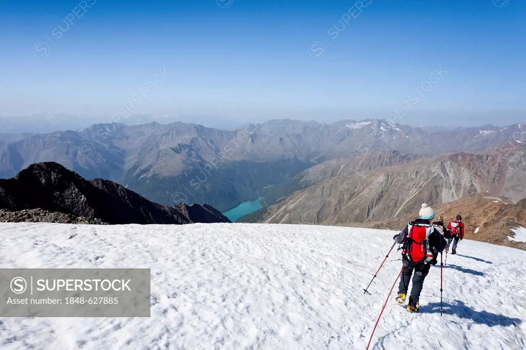 Hikers descending from Similaun mountain, on Niederjochferner glacier in the Schnalstal valley above the Fernagt reservoir, province of Bolzano-Bozen,...