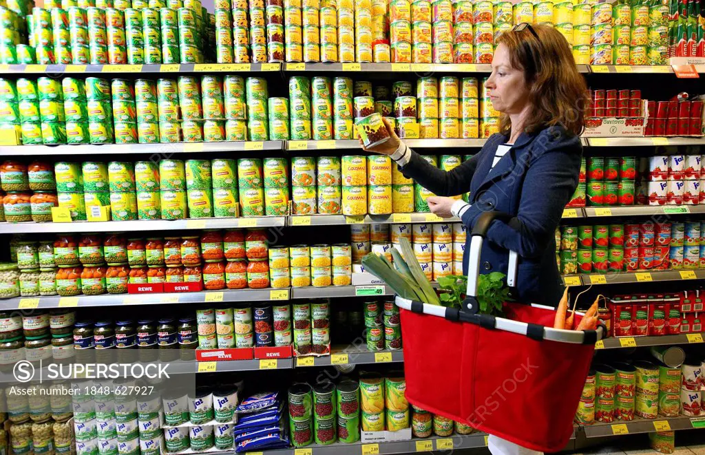 Woman purchasing canned vegetables in a self-service grocery department, supermarket, Germany, Europe
