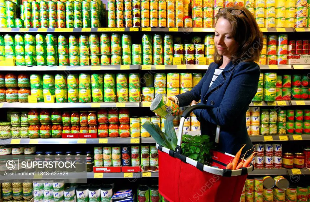 Woman purchasing canned vegetables in a self-service grocery department, supermarket, Germany, Europe
