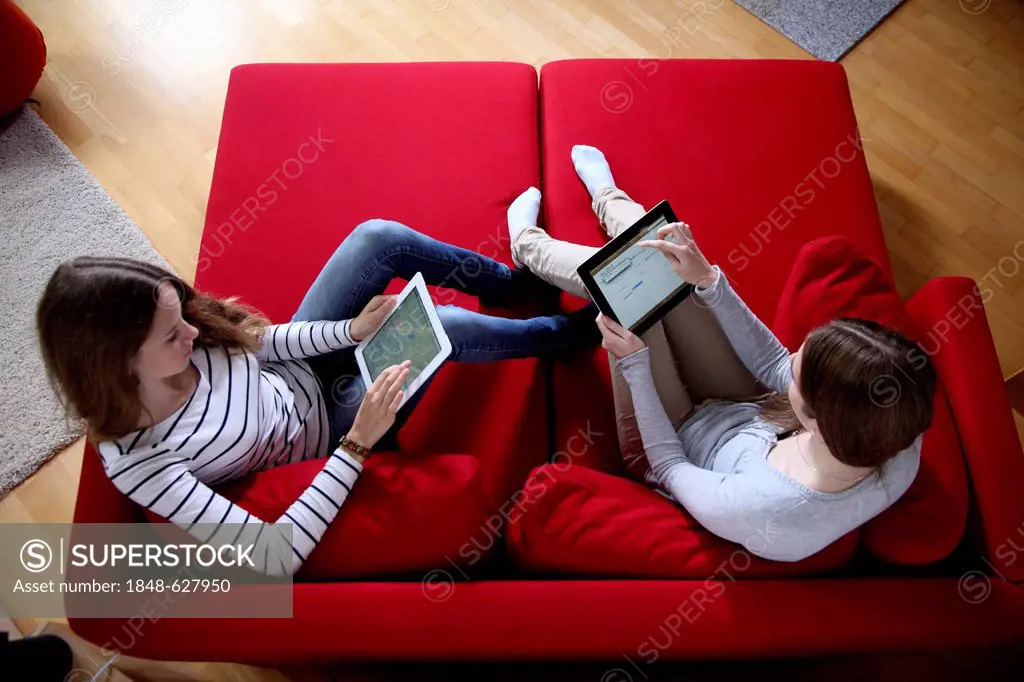 Two girls playing at home with an iPad, tablet computer, wireless internet access