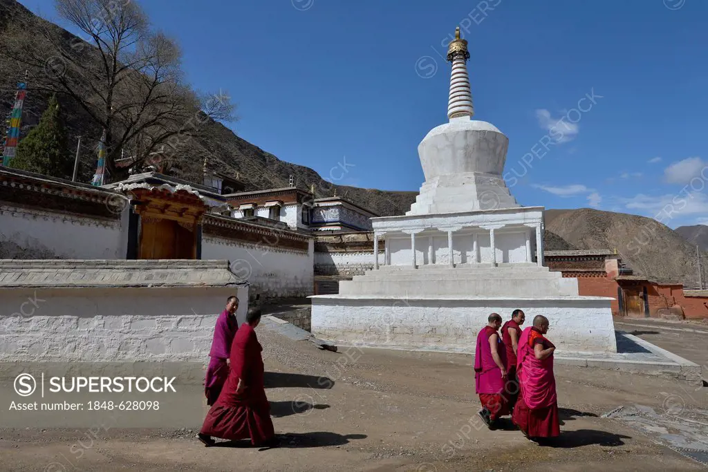 Tibetan Buddhism, monks in front of a white stupa and the monastery buildings, built in the traditional architectural style, Labrang Monastery, Xiahe,...